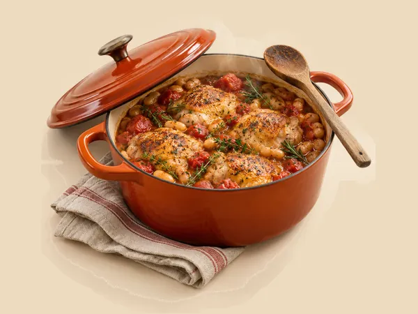 The red pot from the cover, full of chicken thighs, white beans, tomatoes and herbs.